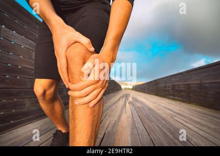 Uomo che tiene la gamba ferita. Lesioni e dolore al ginocchio del corridore. Lesioni dovute all'allenamento Foto Stock