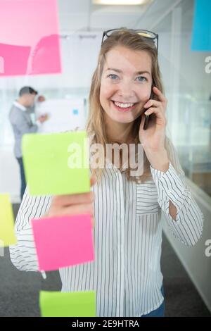 uomo d'affari che parla al telefono mentre si guarda a postare note pratiche Foto Stock