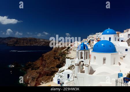 Santorini, Grecia le tradizionali case bianche e chiese con cupole blu coprono la scogliera della Caldera a Oia. Foto Stock