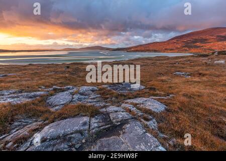 Isola di Lewis e Harris, Scozia: Massi ambientato nel machair con l'ampia distesa di Luskentire spiaggia al tramonto sull'isola di Harris Foto Stock