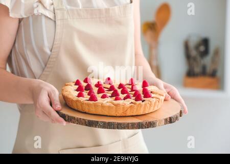 Donna con gustosa torta di lamponi in cucina, primo piano Foto Stock