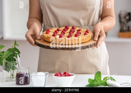 Donna con gustosa torta di lamponi in cucina, primo piano Foto Stock