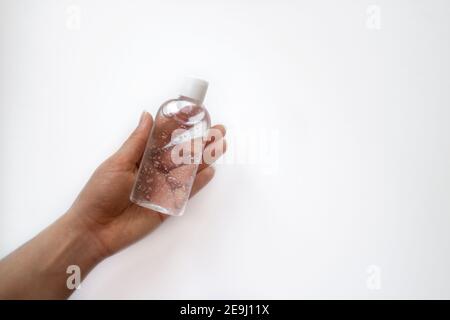 Vasetto con gel antisettico in una mano su fondo bianco. Detergente antimicrobico. Foto Stock