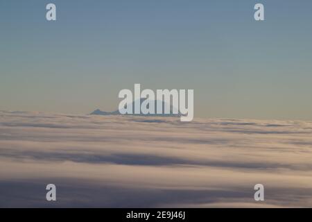 Monte Rainier emergente dalle nuvole, visto da un aereo, Washington, Stati Uniti Foto Stock