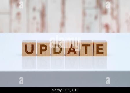 Cartello con il messaggio "Update" su blocchi di legno posti su un tavolo bianco con parete di legno sullo sfondo. Foto Stock