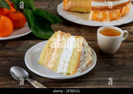 Pezzo di torta con tè verde e mandarino fresco su tavolo di legno. Foto Stock
