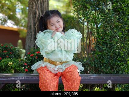 Una giovane ragazza asiatica carina indossa un tradizionale costume tailandese verde e arancione durante il festival di Songkran in Thailandia. Foto Stock