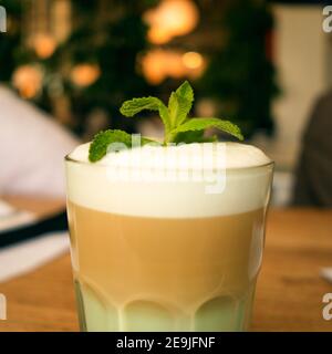 Bevanda preferita. RAF con latte, sciroppo, panna montata e foglie di menta. Un bicchiere di caffè. Primo piano. Foto Stock