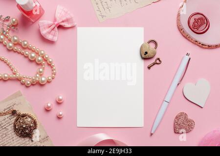 Biglietto d'auguri d'amore su sfondo rosa Mockup vuoto. Oggetti femminili sparsi intorno come perle, cuori, arco, chiave d'amore e serratura, nastro, smalto per unghie, m Foto Stock