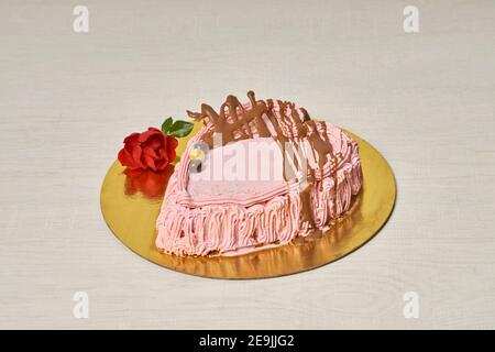 Torta di fragole e crema fatta a mano per San Valentino, a forma di cuore e su base dorata Foto Stock