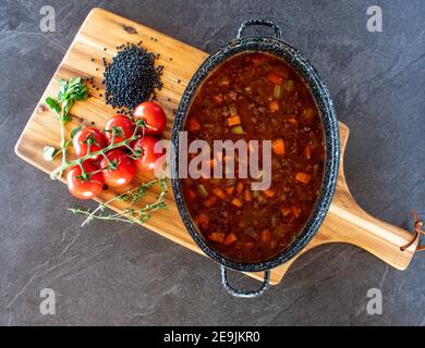 stufato di carne macinato con lenticchie beluga e verdure in un salsa piccante di pomodoro servita in una pentola dall'alto Foto Stock