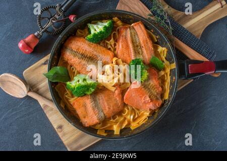 una padella con salmone fritto e pasta cremosa Foto Stock