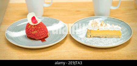 Due tazze bianche di caffè con diversi pezzi di torte in piattini sul tavolo di legno Foto Stock