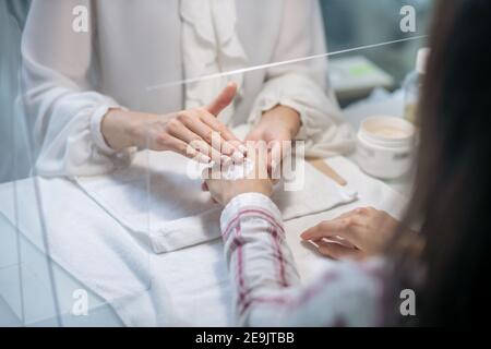 Primo piano immagine di mani estetiste che applicano crema ai clienti mani Foto Stock