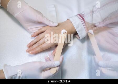 Primo piano immagine delle mani in guanti applyng crema su una mano Foto Stock