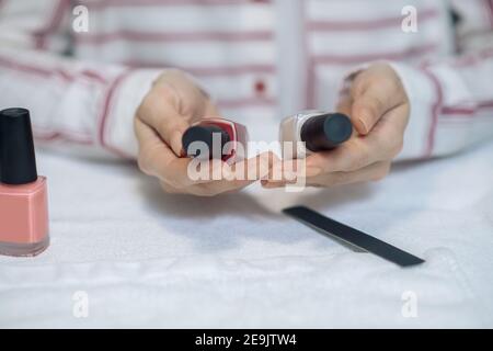 Primo piano delle mani femminili che tengono due bottiglie di chiodo polacco Foto Stock