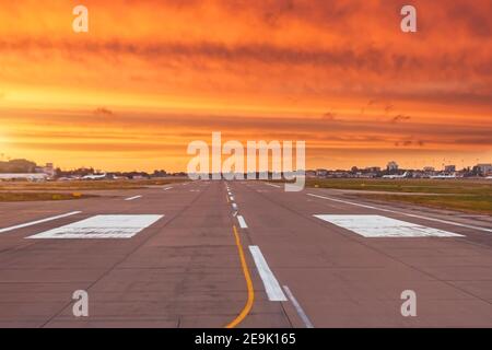 La pista è libera pronta per il decollo e l'atterraggio dell'aereo, sullo sfondo del tramonto più luminoso con le nuvole a strisce testurizzate di r Foto Stock
