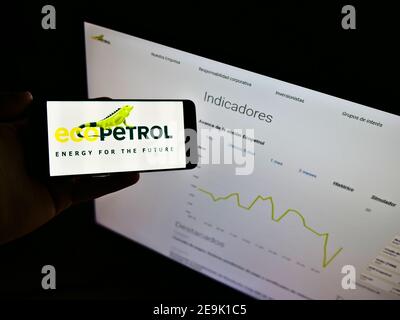 Persona che detiene cellulare con logo della società colombiana di petrolio e gas Ecopetrol S.A.on mostra di fronte al sito web con grafico. Mettere a fuoco lo schermo del telefono. Foto Stock