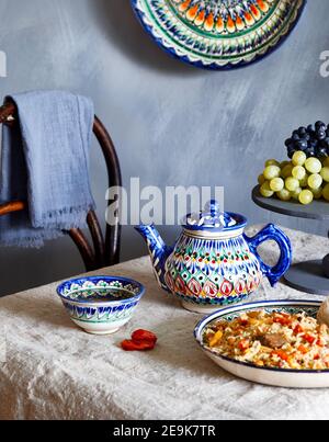 Usbeco cibo tradizionale pilaf, tè verde e frutta in piatto nazionale durante il festival di Nauryz su sfondo blu scuro Foto Stock