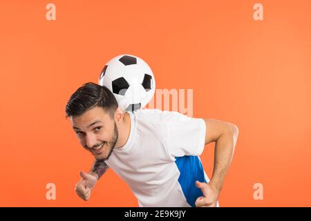 Giocatore di calcio del calcio del Young Man che bilancia la palla di calcio sul schiena del collo e dare pollici in su Foto Stock