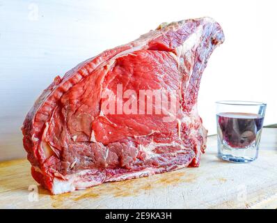 Bistecca di manzo alle ossa, ben stagionata, pronta per il vostro barbecue e pranzo, bistecca fiorentina, con un bicchiere di buon vino rosso genuino Foto Stock