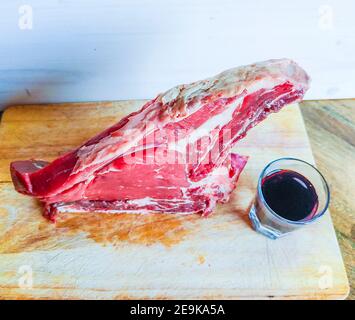 Bistecca di manzo alle ossa, ben stagionata, pronta per il vostro barbecue e pranzo, bistecca fiorentina, con un bicchiere di buon vino rosso genuino Foto Stock