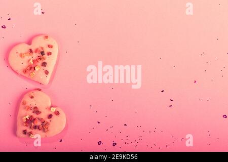 San Valentino biscotti a forma di cuore fragole secche su sfondo rosa con confetti. Vista dall'alto. Spazio di copia. Concetto d'amore, dolcetti di San Valentino Foto Stock