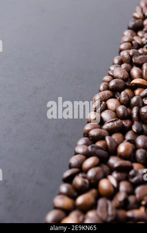 Chicchi di caffè su sfondo scuro, disposti in modo ordinato, close-up still life, flat lay, studio interno, sfondo, carta da parati con spazio per la copia, spazio per il testo Foto Stock