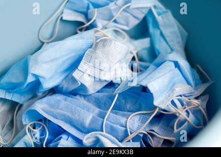 Molte maschere mediche blu impilate. Molte maschere mediche di protezione su sfondo blu. Problemi di auto-conservazione, isolamento Foto Stock