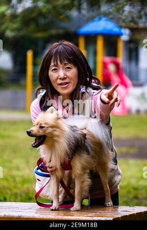 Una donna giapponese e il suo cane nel parco Foto Stock