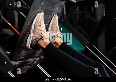 Primo piano di una donna che fa la pressione delle gambe nel palestra Foto Stock