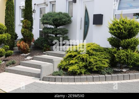 Cortile anteriore ordinato e ordinato con gradini a blocco solido, ghiaia decorativa e piantatura Foto Stock