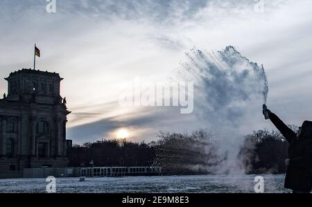 Berlino, Germania. 01 Feb 2021. Sul prato di fronte al Reichstag, un uomo lancia l'acqua bollente da una bottiglia nell'aria, che si congela immediatamente a temperature inferiori allo zero. Credit: Paul Zinken/dpa-Zentralbild/ZB/dpa/Alamy Live News Foto Stock