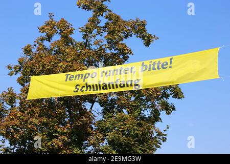 Bandiera sopra la strada con le lettere tedesche „Slow down please, scuola starter" (Germania) Foto Stock