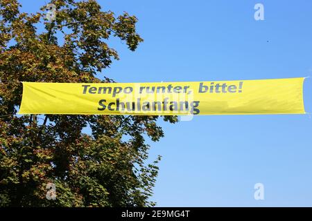 Bandiera sopra la strada con le lettere tedesche „Slow down please, scuola starter" (Germania) Foto Stock