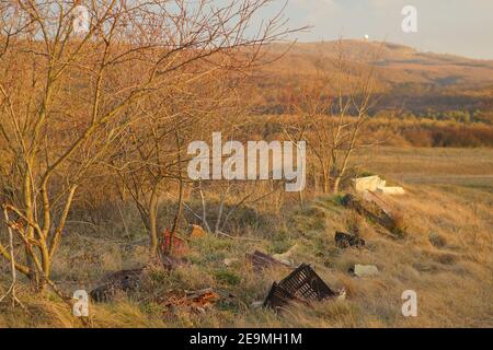 Bakonykoppany, Ungheria - Febr 03, 2021: Una discarica illegale di rifiuti ai piedi delle colline sulla montagna Bakony in Ungheria (Kőris-hegy è visibile nel backgr Foto Stock