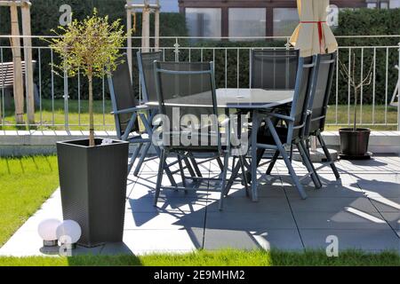 Moderna terrazza giardino con piastrelle grigie e mobili da giardino Foto Stock