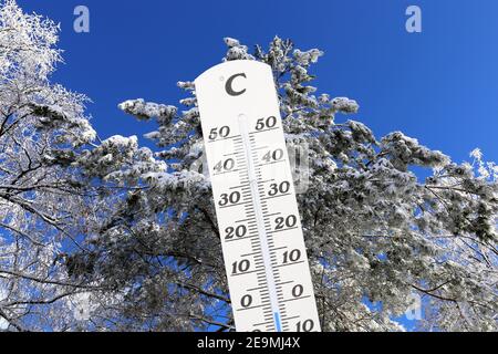Immagine simbolo: Il termometro con unità di misura Celsius mostra le temperature fredde, un paesaggio invernale sullo sfondo Foto Stock