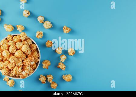 Popcorn al caramello in una tazza su sfondo blu, vista dall'alto. Dolce fresco e saporito Foto Stock
