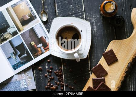 Vista dall'alto di una tazza di caffè su un tavolo con cioccolato e riviste Foto Stock