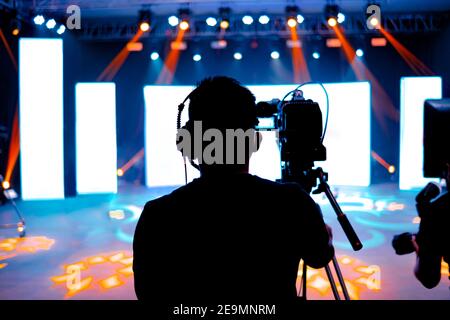 Cameraman professionale - copertura dell'evento con un video, una silhouette cameraman sulle notizie dal vivo in studio, fuoco selettivo Foto Stock