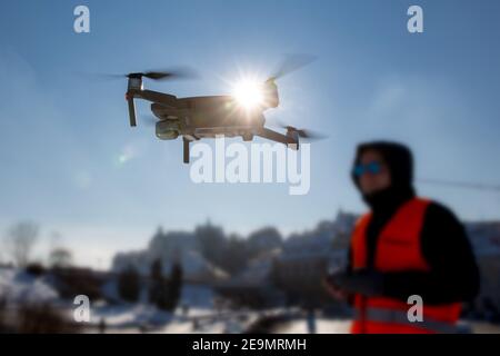 Primo piano immagine di un dron e di una siluetta pilota in luce del tramonto e sfondo blu del cielo, l'uomo che vola un drone in città utilizzando un contr Foto Stock