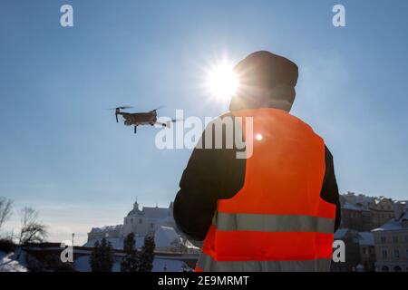 Primo piano immagine di un dron e di una siluetta pilota in luce del tramonto e sfondo blu del cielo, l'uomo che vola un drone in città utilizzando un contr Foto Stock