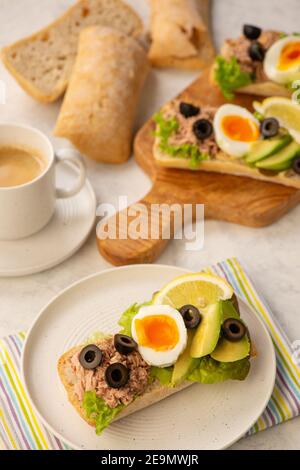 Panini con tonno, uova, olive e avocado su sfondo chiaro. Foto Stock