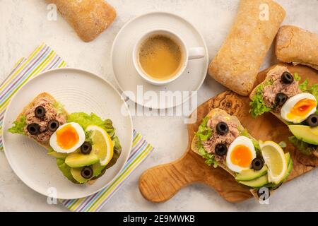 Panini con tonno, uova, olive e avocado su sfondo chiaro. Foto Stock