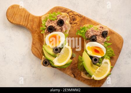 Panini con tonno, uova, olive e avocado su sfondo chiaro. Foto Stock