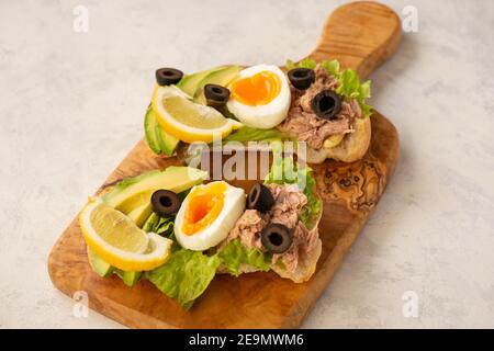 Panini con tonno, uova, olive e avocado su sfondo chiaro. Foto Stock