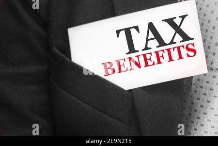Uomo d'affari mantiene una carta con testo benefici fiscali nella tasca superiore del suo vestito. Concetto di tasse e tasse. Foto Stock