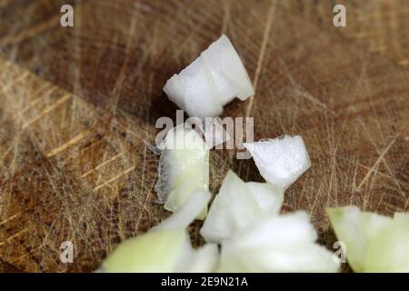 Preparazione degli alimenti per la cottura: Pezzi di cipolla gialla tritati in un closeup. Verdure sane da usare per un'insalata o un'omelette. Cucina casalinga. Foto Stock