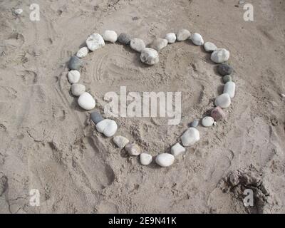 Pietre nere e bianche del cuore sulla sabbia Foto Stock